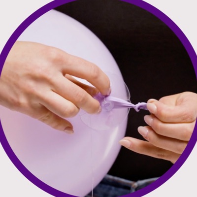 Close up of hands pulling balloon knot through plastic disc